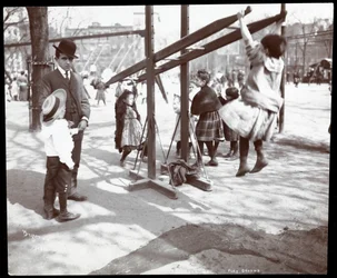 Uitzicht op een man die toezicht houdt op kinderen die spelen op speeltoestellen in Tompkins Square Park, op Arbor Day, New York, 1904